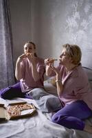 vieux mère et âge moyen fille en mangeant Pizza et en train de regarder une film à Accueil photo