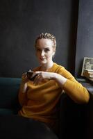 portrait de une élégant âge moyen femme dans une Jaune chandail en buvant café dans une café photo