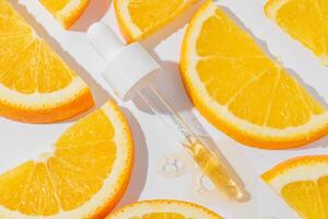 cosmétique pipette avec vitamine c sérum sur blanc Contexte avec des oranges fermer. élégant concept de biologique essences, beauté et santé des produits. moderne apothicaire. proche en haut photo