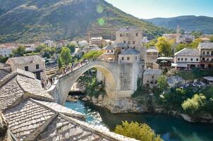 vue de le vieux pont dans Mostar ville dans Bosnie et herzégovine pendant une ensoleillé journée. neretva rivière. unesco monde patrimoine placer. gens en marchant plus de le pont. photo