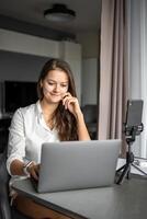 une Jeune femme blogueur conduit un éducatif diffuser sur une portable dans social réseau dans Accueil lieu de travail, en ligne enseignement concept photo