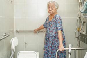 une vieille femme asiatique âgée utilise un rail de support de toilette dans la salle de bain, une barre d'appui de sécurité pour main courante, la sécurité dans l'hôpital de soins infirmiers. photo