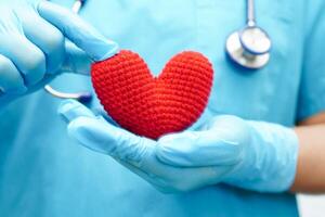 femme médecin asiatique tenant un coeur rouge pour la santé à l'hôpital. photo