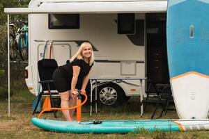 une femme gonfle une sup-board pour nager près sa camping car photo