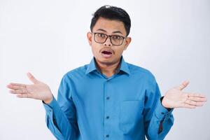 confus Beau Jeune asiatique homme avec des lunettes dans portant chemise haussant les épaules mains de côté et à la recherche déçu isolé sur blanc Contexte photo
