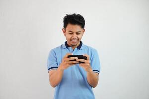 souriant ou content portrait Jeune asiatique homme en jouant Jeu avec téléphone intelligent isolé sur blanc Contexte photo