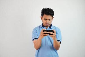 Jeune asiatique homme sérieux et concentré visage en jouant Jeu avec téléphone intelligent isolé sur blanc Contexte photo