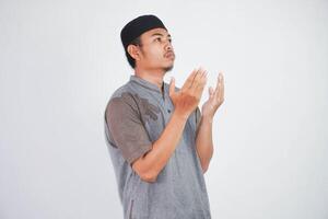 religieux Jeune asiatique musulman homme avec ouvert yeux prier, en portant paumes visage en haut, chuchotement prier, isolé sur blanc Contexte. religion Islam, croire concept photo