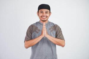 Jeune asiatique musulman homme portant koko vêtements souriant à donner salutation pendant Ramadan et eid Al fitr fête isolé sur blanc Contexte photo