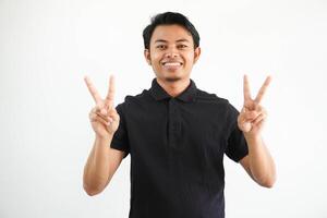 Jeune asiatique homme souriant content avec tous les deux main montrant paix signe portant noir polo t chemise isolé sur blanc Contexte photo