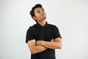 Jeune asiatique homme dans décontractée noir polo t chemise avec bras franchi fatigué de une répétitif tâche à la recherche à caméra studio coup isolé sur blanc Contexte photo