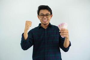 Jeune asiatique homme serré poing tandis que en portant Indonésie papier argent et montrant excité expression isolé sur blanc Contexte photo