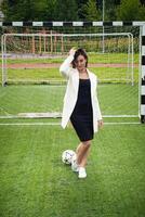 portrait de une magnifique femme Football joueur dans une strict Bureau costume. photo