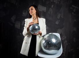 portrait de une femme en portant une argent disco balle. pris dans une photo studio.