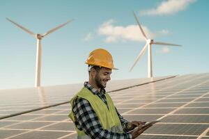 Jeune ingénieur en train de regarder sur numérique tablette le Nouveau vert plan pour alternative énergie avec vent turbine et solaire panneau - innovation et vert Puissance concept photo