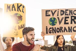 groupe manifestants protester contre Plastique la pollution et climat changement - multiracial gens combat sur route en portant bannières sur environnements désastres - global chauffage concept photo