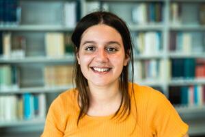 content Jeune étudiant souriant dans le caméra à l'intérieur Université bibliothèque photo