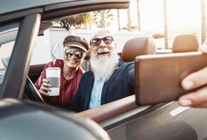 content Sénior couple prise selfie sur Nouveau moderne convertible voiture - mature gens ayant amusement ensemble fabrication soi Photos pendant route voyage vacances - personnes âgées mode de vie et Voyage transport concept