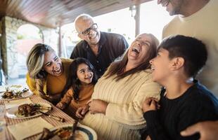 content Latin famille ayant amusement déjeuner ensemble à Accueil photo