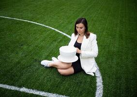 une affaires femme avec une grand tasse, séance sur une vert pelouse dans le parc. photo