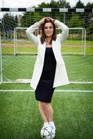 portrait de une magnifique femme Football joueur dans une strict Bureau costume. photo