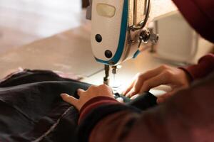 une femme mains sont adapté avec moderne couture Machines à travail, couture vêtements coussins et réparer techniques. photo