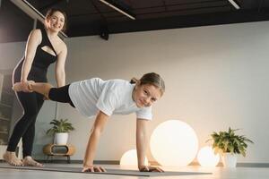 maman et adolescent fille faire gymnastique ensemble dans le aptitude chambre. une femme et une fille train dans le Gym photo