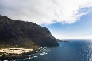 rugueux rocheux falaises sur le île de tenerife.noir plage sur le canari îles. rochers, volcanique osciller, atlantique océan photo