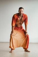 une homme dans un Orange costume Est-ce que yoga par en mouvement le sien abdominal muscles dans le salle de sport. le concept de santé photo