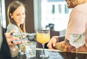 barman en train de préparer des cocktails verser en dehors citron vert - content copains attendre pour les boissons à compteur dans américain bar - personnes, divertissement, mode de vie concept - concentrer sur Haut cristal verre photo