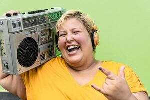 content plus Taille femme ayant amusement écoute la musique avec sans fil écouteurs et ancien boombox stéréo photo