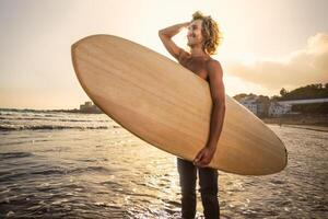 Jeune surfeur ayant amusement profiter une le surf journée à le coucher du soleil temps - extrême sport mode de vie gens concept photo