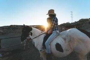 content famille mère et fille ayant amusement équitation cheval à l'intérieur ranch photo