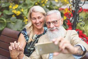 content Sénior couple prise selfie avec mobile intelligent téléphone Extérieur - mature retraité gens ayant amusement avec Nouveau La technologie social médias applications - personnes âgées retraité l'amour mode de vie et technologie concept photo