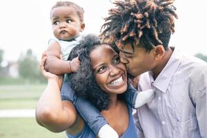 content noir famille ayant amusement dans une parc Extérieur - mère et père avec leur fille profiter temps ensemble dans une fin de semaine journée - l'amour et bonheur concept photo