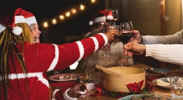 content multiracial Sénior copains grillage avec rouge du vin des lunettes pendant Noël vacances dîner fête sur patio maison fête photo