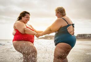 content plus Taille femmes ayant amusement sur le plage pendant été vacances - courbée sur de soi gens mode de vie concept photo