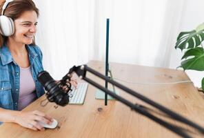 content femme enregistrement une Podcast en utilisant ordinateur et microphone de sa Accueil studio photo