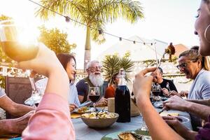content famille Faire une dîner pendant le coucher du soleil temps Extérieur - groupe de diverse copains ayant amusement à manger ensemble à l'extérieur - concept de mode de vie personnes, nourriture et fin de semaine Activités photo