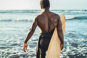 Masculin afro surfeur ayant amusement surfant pendant le coucher du soleil temps - africain homme profiter le surf journée - extrême sport mode de vie gens concept photo