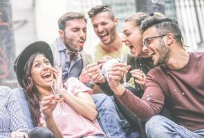 groupe de content copains fabrication fête en buvant Champagne tandis que lancement confettis Extérieur - Jeune gens en riant et ayant amusement célébrer vacances avec alcool, confettis et cierges magiques - jeunesse concept photo