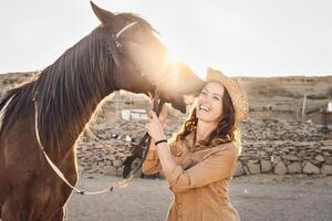 Jeune agriculteur ayant amusement avec les chevaux à l'intérieur stable - content fille en jouant avec animaux dans corral ranch - Humain et animaux relation concept photo