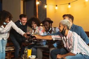 content multiracial copains ayant amusement pendant vacances grillage avec des cocktails et rouge du vin sur patio maison fête photo