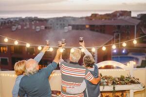 content Sénior copains applaudissement et grillage avec rouge du vin sur toit - mature gens ayant amusement et en buvant à barbecue fête dans terrasse - concept de amitié, retraités et retraite photo