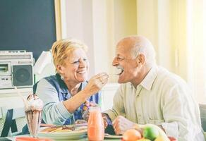 content Sénior couple en mangeant Crêpes à petit déjeuner dans une bar restaurant - vieux gens ayant amusement profiter repas à le déjeuner - concept de personnes âgées retraité la personne des moments - ancien filtre - concentrer sur Masculin visage photo