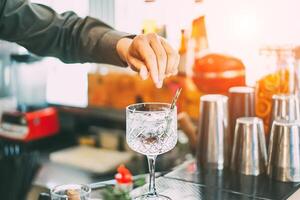 barman mélange une cocktail dans une cristal verre avec aromatique herbes dans américain bar à le coucher du soleil Extérieur - barman à travail - profession, bar mode de vie concept photo