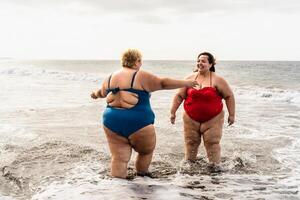 content plus Taille femmes ayant amusement sur le plage pendant été vacances - courbée sur de soi gens mode de vie concept photo