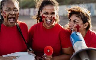 femelle Football Ventilateurs exultant tandis que en train de regarder une football Jeu à le stade - femmes avec peint visage et mégaphone encourageant leur équipe - sport divertissement concept photo