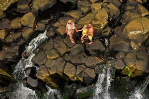 famille sur le Contexte de le rochester cascade sur le île de maurice de une hauteur.cascade dans le jungle de le tropical île de maurice photo