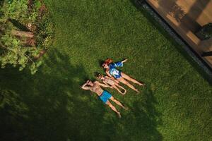 Haut vue de une content famille dans maillots de bain mensonge sur le vert herbe photo